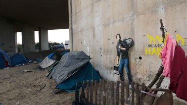 The Jungle refugee camp, Calais. QUANDO SMURARE IL MEDITERRANEO è davvero una pratica attuale sui muri, l'opera appena realizzata da Banksy e postata sul suo sito: il vandalo di qualità ha rappresentato Steve Jobs - figlio di migranti siriani - in fuga, su un muro di Calais, in Francia, luogo di approdo di tantissime persone dal mare. qui un bel racconto: http://cappellodicarta.com/…/banksy-e-limmigrazione-raccon…/